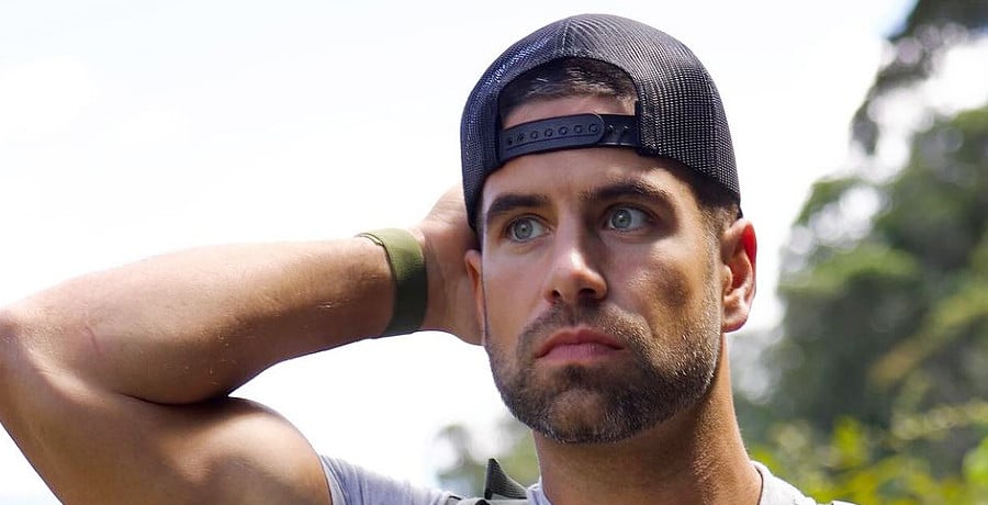 A man with brown hair showing off his arm muscle